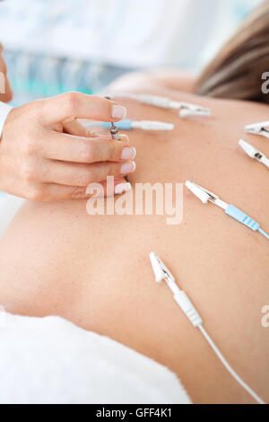 Médecin appliquant l'électroacupuncture sur dos du patient Banque D'Images
