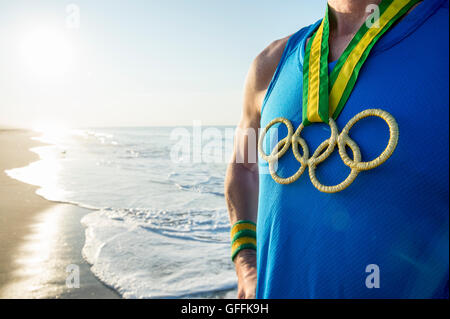 RIO DE JANEIRO - le 10 mars 2016 : Athlète portant des anneaux olympiques médaille d'élève face à Sunrise Beach shore. Banque D'Images