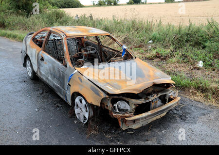 Les restes d'une voiture (qui a fondu le tarmac en dessous) dans le Wiltshire, Royaume-Uni. Banque D'Images