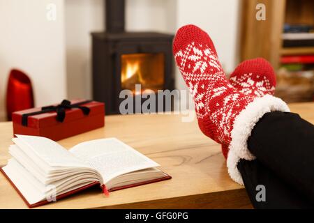 Femme de détente à la maison devant un bon feu à Noël Banque D'Images