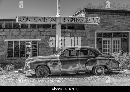 Un traitement monochrome artistique d'une vieille voiture en face d'un ancien poste de traite dans le désert américain Banque D'Images