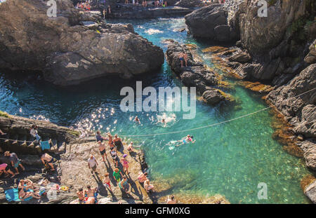 Les touristes la natation dans la mer Méditerranée, au large de la côte du village de Manarola. Banque D'Images