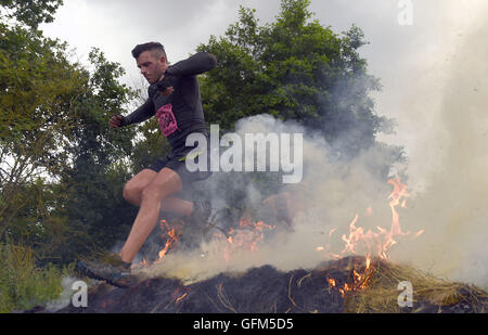 Un concurrent saute par dessus le feu au cours d'Ortie Tough Guy Warrior 2016 à South tonne Farm dans le Staffordshire. Banque D'Images