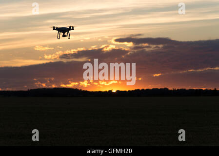 Drone silhouetté contre coucher du soleil orange Banque D'Images