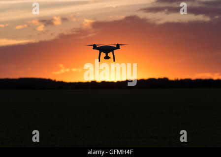 Drone silhouetté contre coucher du soleil orange Banque D'Images