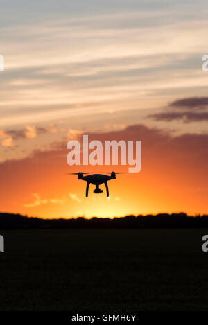 Drone silhouetté contre coucher du soleil orange Banque D'Images