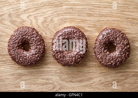 Trois beignes au chocolat sur la table rustique en bois Banque D'Images