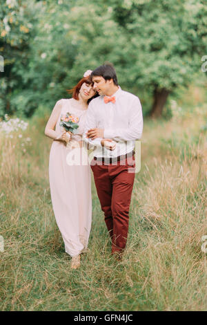 Aimer juste marié robe de mariage couple hipster et costume sur champ vert en forêt à la journée ensoleillée Banque D'Images