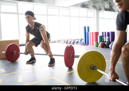Les jeunes hommes chinois barbell levage at gym Banque D'Images