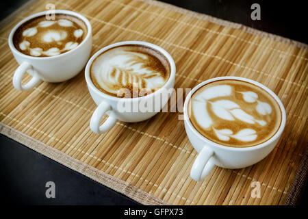 Trois tasses de café latte avec trois formes de latte art