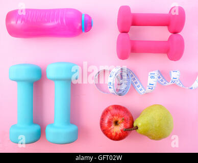Télévision et de remise en forme avec les Dumbells rose et bleu et accessoires sur une table en bois de rose. Banque D'Images