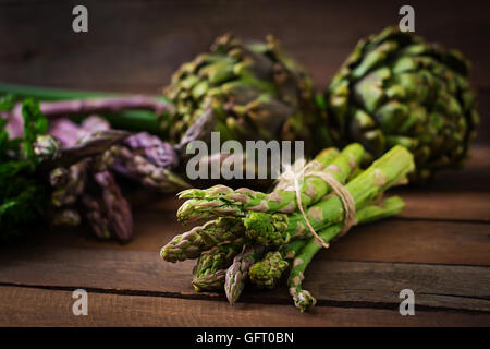 Les asperges et les artichauts avec des herbes sur un fond de bois Banque D'Images