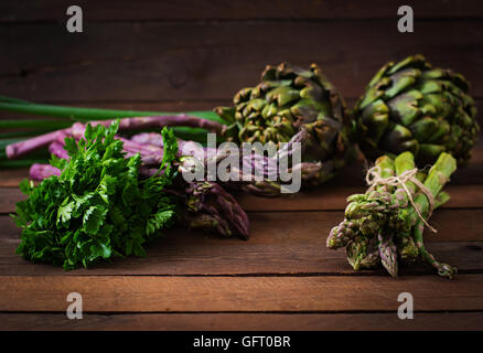 Les asperges et les artichauts avec des herbes sur un fond de bois Banque D'Images