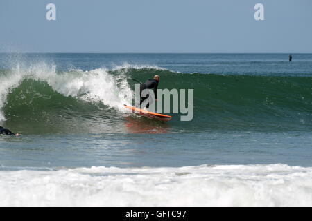 Stand Up Paddle d'embarquement - la nouvelle eau-sport du 21e siècle. Un internaute bas tourne sur le visage d'un parfait green wave sur Gower en UK Banque D'Images