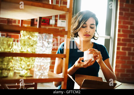 Jeune femme dans un magasin tenant un petit objet en céramique Banque D'Images