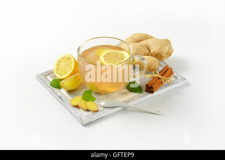 Tasse de thé au gingembre avec le citron, le gingembre et la cannelle sur planche à découper en bois Banque D'Images