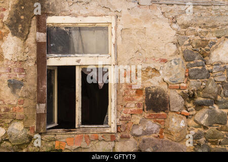Fenêtre d'une maison abandonnée. Du verre brisé. Mur de l'édifice avec de nombreux détails de la couleur des briques et pierres. Banque D'Images