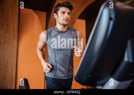 Les jeunes sportifs et de course sur tapis roulant dans une salle de sport Banque D'Images