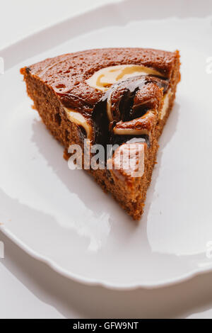 Morceau de gâteau avec remplissage de truffes close-up sur une plaque blanche. Banque D'Images