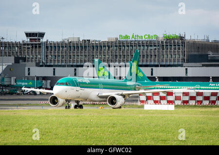 Aer Lingus avion sur le tarmac de l'aéroport de Dublin avec l'aéroport de Dublin signe sur le terminal derrière Banque D'Images
