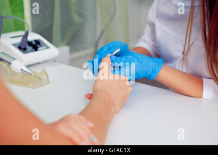 Libre shot of a woman in nail salon receiving manicure par boucher avec fichier. obtenir . Clous au client. Banque D'Images