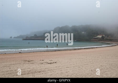 Paddleboarders dans la mer à St Brelade's bay, Jersey, comme le brouillard de mer en rouleaux Banque D'Images