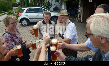 Hotel Gasthof Brüggler Fritz homme barbu en pantalons de cuir et une chemise traditionnelle boit de la bière avec des invités en face de sa maison, haut au-dessus de la ville de Zell am See en Autriche le 15 juin 2016. Avec sa barbe Garibaldi il a été vice-Champion d'Europe, Champion du Monde et même barbe Olympia gagnant. Le 06 août 2016, il sera à la 2ème du championnat autrichien internationale des barbus dans le cadre de la 34e fête du village à Dorfgastein. En 2012, il a été attribué pour la plus belle barbe Garibaldi de l'univers. Hotel Gasthof Brüggler Fritz dirige son propre petit musée de couture avec plus de 2500 machines à coudre et Banque D'Images