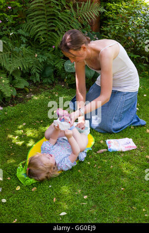 Ma mère parent accompagnant l'évolution des couches lavables nappy change de bébé tout-petit. Jardin plein air / Extérieur / Extérieur / plein air / outdoor Banque D'Images