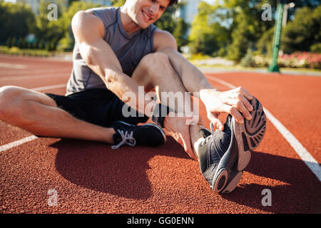 Portrait d'un coureur souffrant de crampes de jambe dans le stade Banque D'Images