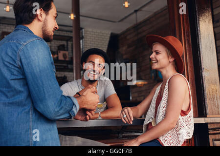 Les jeunes hommes et les femmes siégeant ensemble et parler dans un café. Groupe de jeunes amis dans un café. Banque D'Images