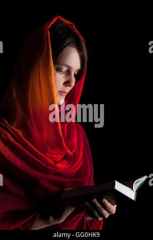 Femme lisant une Bible dans la nuit. Isolé sur un fond noir Banque D'Images