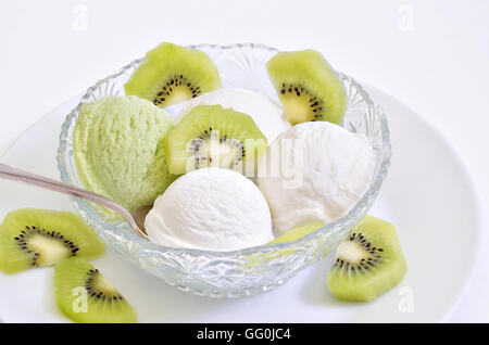 Glace vanille et crème glace kiwi avec des tranches de kiwi dans un bol sur la plaque blanche, macro, fond blanc Banque D'Images