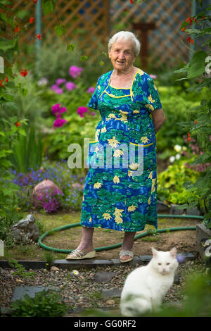 Femme âgée debout dans jardin avec chat. Banque D'Images