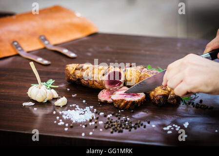 La sculpture au service de la viande de porc rôti roll repas dans un style rustique avec des assaisonnements Banque D'Images