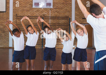 L'exercice de l'enseignement de l'enseignant à l'école les enfants dans la cour de basket-ball Banque D'Images