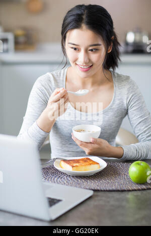 Jeune femme chinoise à l'aide d'ordinateur portable pendant le petit-déjeuner Banque D'Images