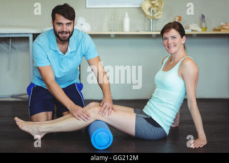 Physiothérapeute faisant la thérapie de la jambe d'une femme à l'aide du rouleau en mousse Banque D'Images