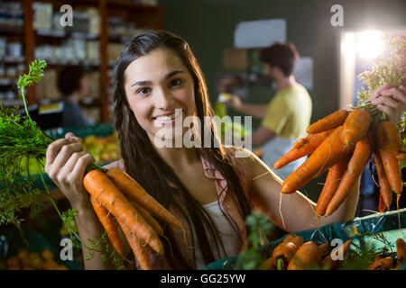 Portrait of Beautiful woman holding bunch of fresh carrots dans la section bio Banque D'Images