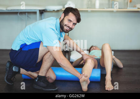 Physiothérapeute faisant la thérapie de la jambe d'une femme à l'aide du rouleau en mousse Banque D'Images