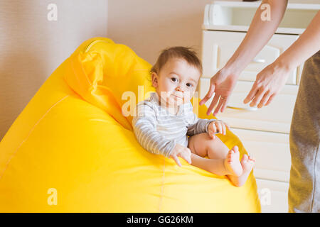 Bébé garçon enfant souriant est assis sur une chaise Banque D'Images