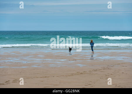 Une femme avec un labrador chien qui court sur une plage à Cornwall UK Banque D'Images