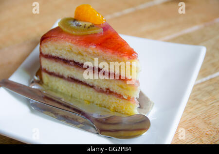 Morceau de gâteau sur une plaque blanche sur table en bois Banque D'Images