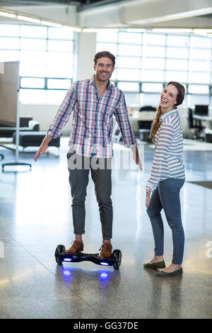 Designer graphique debout sur hover board in office Banque D'Images