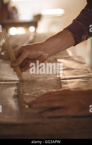 Potter mâle avec des bâtons d'argile de la conception Banque D'Images