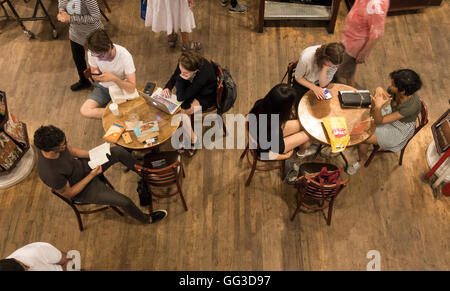 Les jeunes, hommes et femmes, de la lecture, de travailler, de se détendre à la Housing Works Cafe dans Soho à New York City Banque D'Images