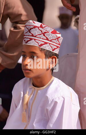 Portrait d'un petit garçon habillé de façon traditionnelle omanaise participant à la marché de chèvre à Nizwa, Oman, Hajar Occidental Banque D'Images