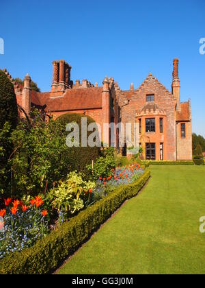 Vue Portrait de Chenies Manor House tulip frontière, l'hellébore, Bleu myosotis et de la pelouse sur le sud ouest de l'édifice. Banque D'Images