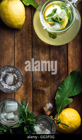 Pichet avec limonade fait maison, de menthe, de citrons frais et des cubes de glace sur fond de bois, vue du dessus, copy space Banque D'Images