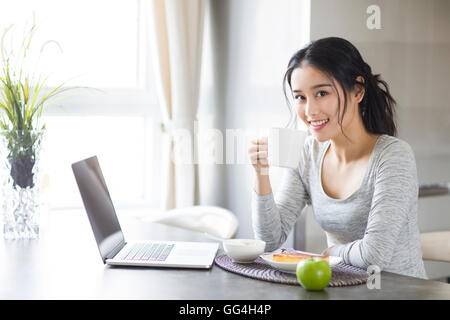 Jeune femme chinoise à l'aide d'ordinateur portable pendant le petit-déjeuner Banque D'Images