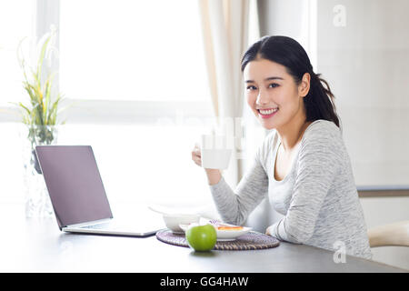 Jeune femme chinoise à l'aide d'ordinateur portable pendant le petit-déjeuner Banque D'Images